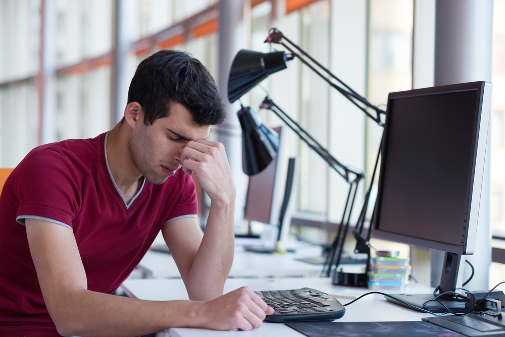 frustrated young business man working on laptop computer at office