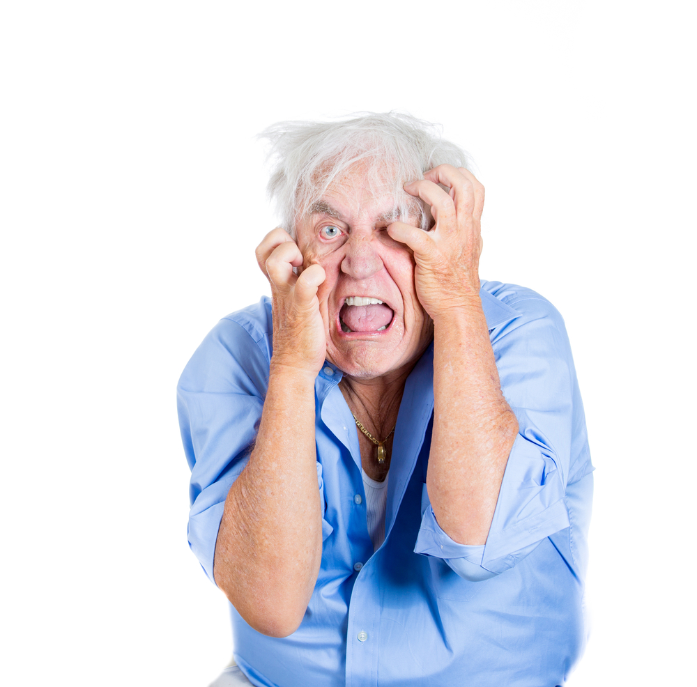 A close-up portrait of an elderly, desperate, mad, looking crazy, desperate man, going insane, isolated on a white background. Human emotions extremes. Loneliness, grief, family loss.