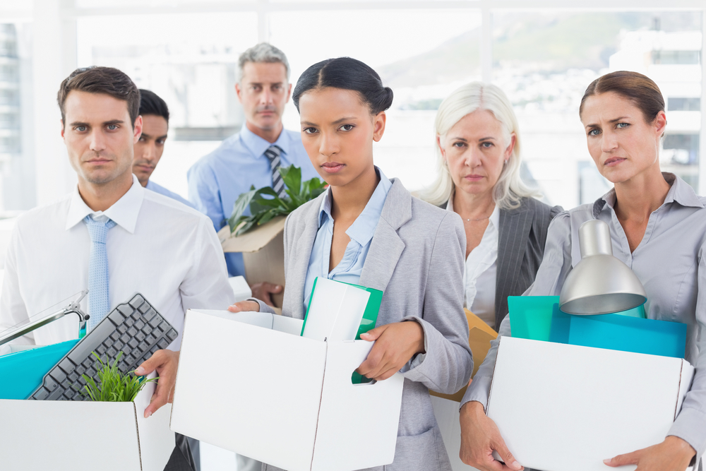 Unhappy fired business people holding box in office