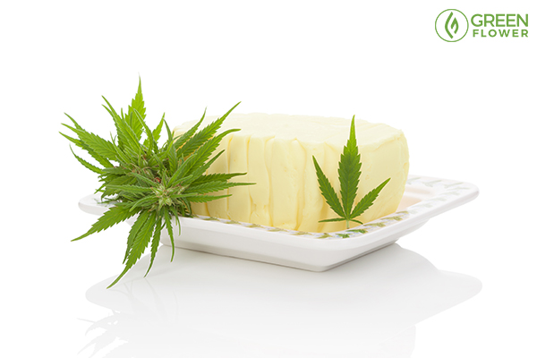 cannabis-infused butter on a tray with fresh marijuana leaves and buds