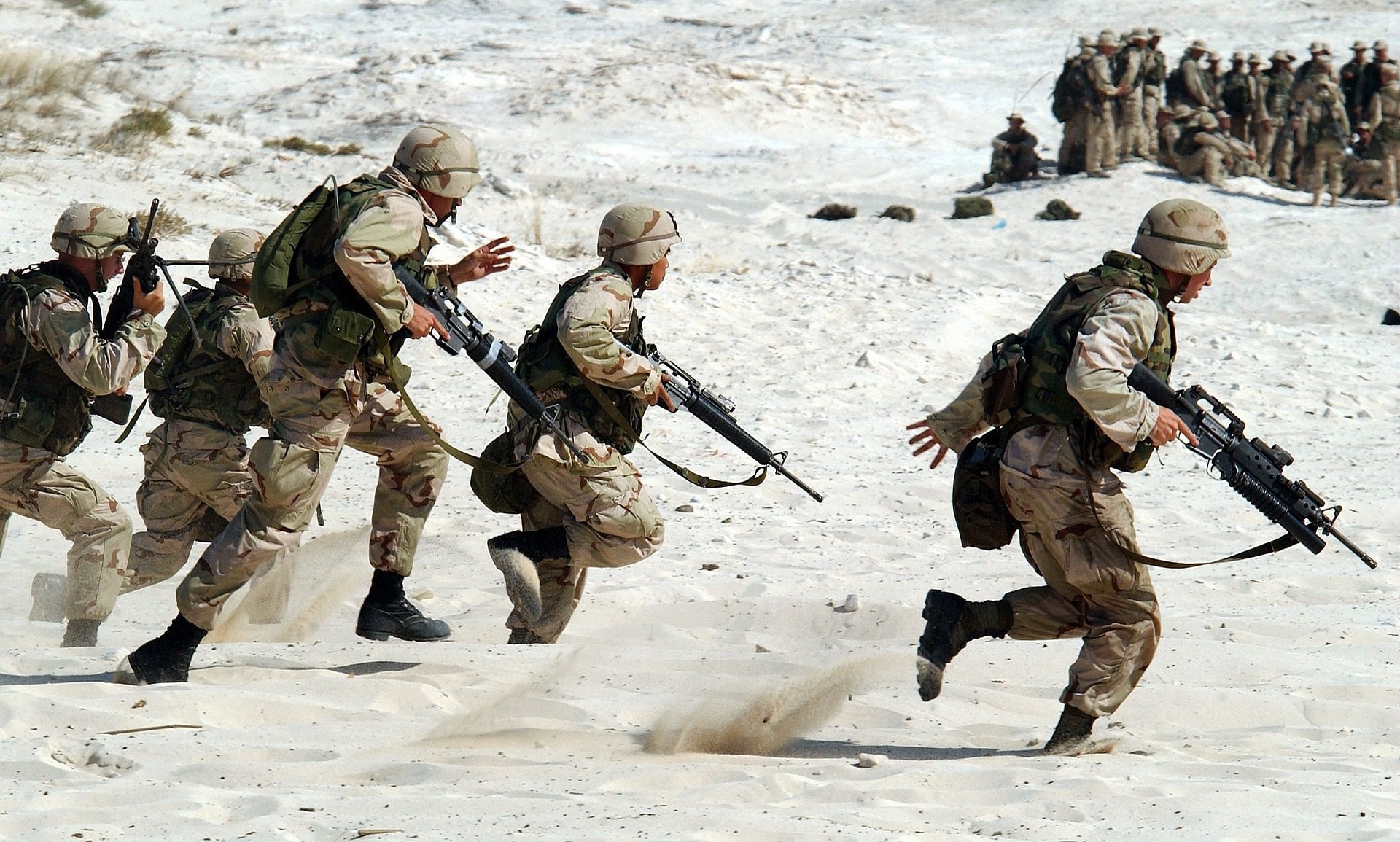 Soldiers carrying weapons running as part of training in the desert
