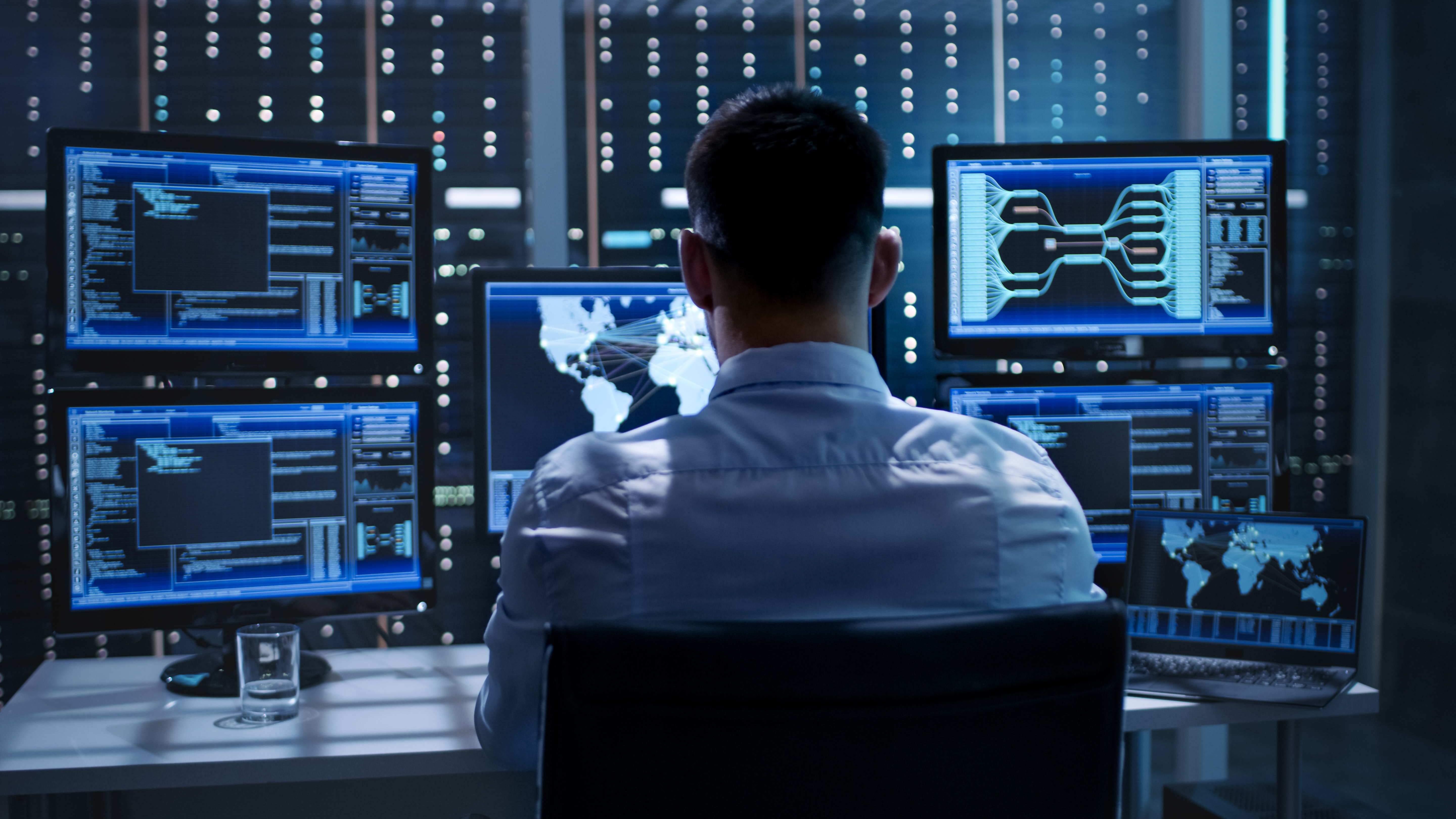 An employee sitting in front of multiple computer screens, implementing network segmentation best practices for defense manufacturing companies